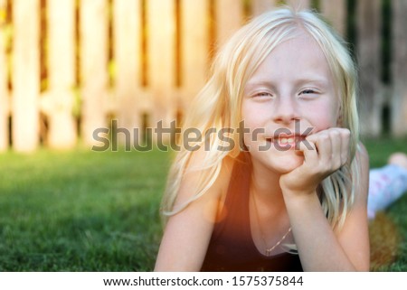 beautiful blonde smiling  girl  lying  on the grass on a summer day