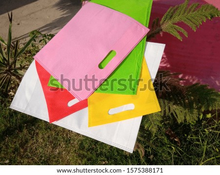 Colored Non Woven Bags on Green Background 