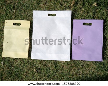3 Non Woven Eco Bags on Green Grass Background. Shopping & Gift Bags