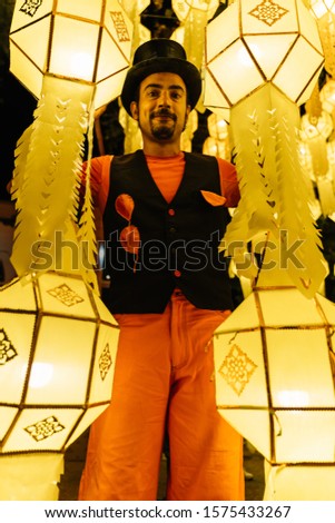 Stock vertical photo of a tightrope walker dressed in a black hat surrounded by Chinese lanterns at night