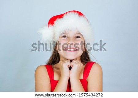 Happy Xmas and New Year holiday. Shocked and surprised kid with red Christmas hat with head in hands. Cheerful smiling little girl opens his mouth in surprise.