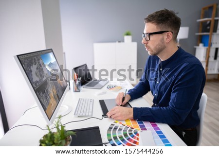 Rear View Of A Man Working On 3D Landscape On Computer In Office