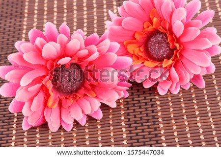 Pink fabric daisies on bamboo background, closeup picture.