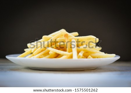 Fresh french fries in white plate with black background / Tasty potato fries for food or snack delicious Italian meny homemade ingredients Royalty-Free Stock Photo #1575501262
