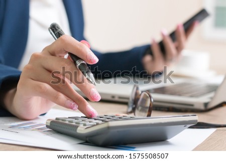 Business woman thinking account, Calculator,  Laptop, business chart and graph document on desk.
