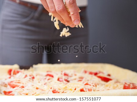 Housewife preparing pizza with cheese
