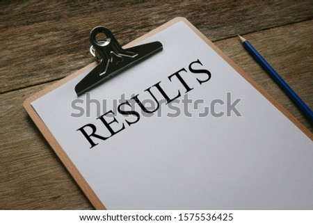 Pencil and clipboard with white paper written with Results on wooden background.