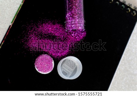 Purple glitter In a clear bottle on the black book.selective focus
