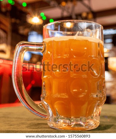 A mug of unfiltered beer, blurred background, bokeh, cafe-restaurant.