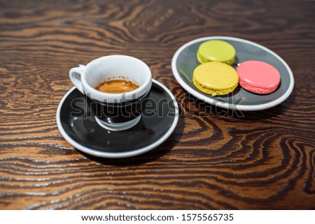 Fresh strong coffee and macaroons on a large beautiful wooden table