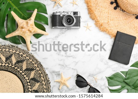 Flat lay composition with professional photographer camera, passport and space for text on white marble table