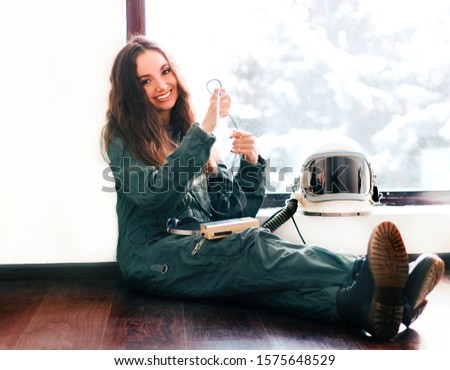 Cute girl in a space suit listening to music. Loft design. Astronaut girl in space helmet. Happy girl smiling. Young girl in an astronaut suit. Space helmet. Nice and kind smile. Background wallpaper.