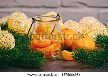 Tangerines with spruce branches and a garland on a background of a brick wall. New Year's still life.