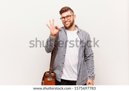 Young modern business man winks an eye and holds an okay gesture with hand.