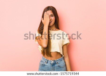 Young slim woman having fun covering half of face with palm.
