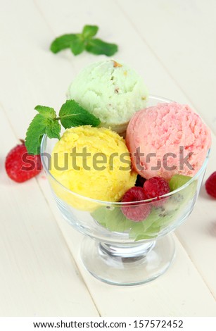 Tasty ice cream scoops, on wooden table