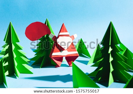 Origami santa claus with a bag of gifts. Cartoon postcard. Stock photo handmade paper.