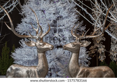 Christmas toys - two figures of glittering deers on the background of a white Christmas tree