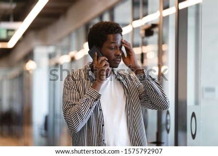 African businessman having difficulties at work solve problems talking using cellular, office worker standing in hallway feels concerned listen client, thinking search solutions make decisions concept Royalty-Free Stock Photo #1575792907