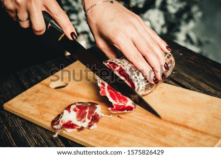 girl cuts cured meat on the kitchen board