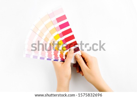 Female hand holding color swatches. Color trend palette. Flat lay, top view. 