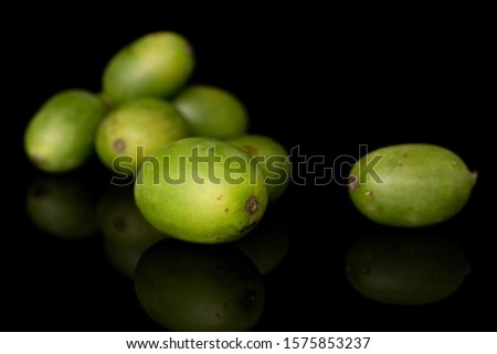 Group of seven whole hardy green kiwi isolated on black glass