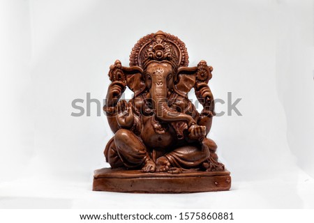 wooden statue of Hindu god Ganesha with a white background, Hindu religion Royalty-Free Stock Photo #1575860881
