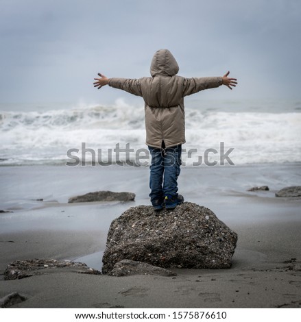 Little boy walking on winter sea beach