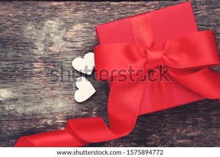 Gift box with ribbon bow and small hearts on grey wooden table