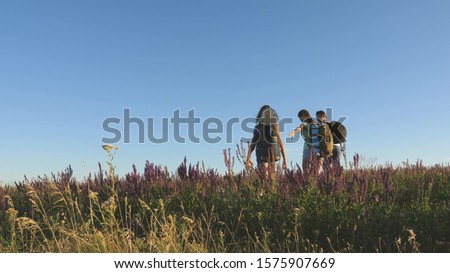 teamwork of tourists. travelers go with backpacks through the meadow. Family of tourists with children in countryside. travelers admire the beautiful scenery and nature. movement to victory.