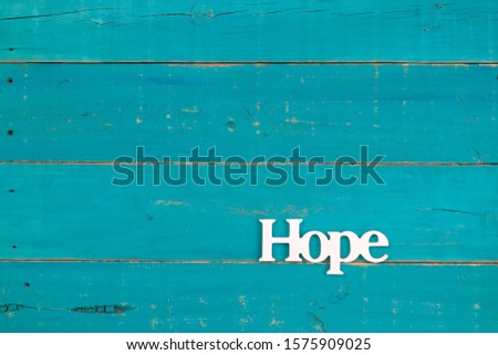 The word Hope hanging on rustic teal blue wood sign; religious holiday background with painted copy space