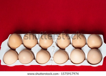 White plastic tray with eggs on red background.