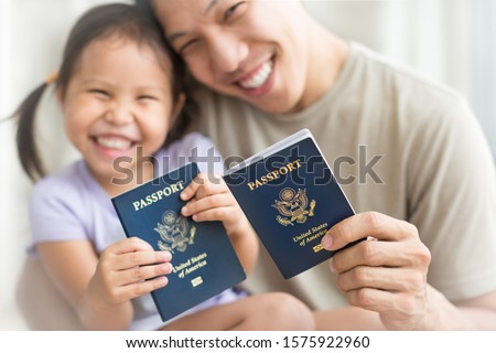 Asian dad and daughter holding amercian passports with pride. Immigration citizenship Royalty-Free Stock Photo #1575922960