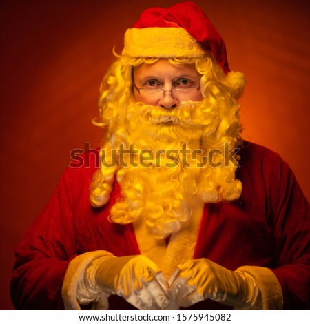 Portrait Santa Claus, old man posing on a dark red background.