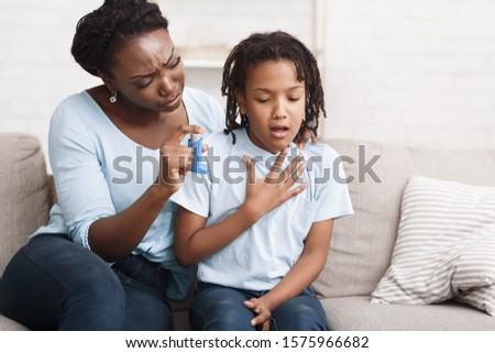 African Girl Having Asthma Attack, Worried Mom Giving Her Inhaler For Relief. Copy space Royalty-Free Stock Photo #1575966682