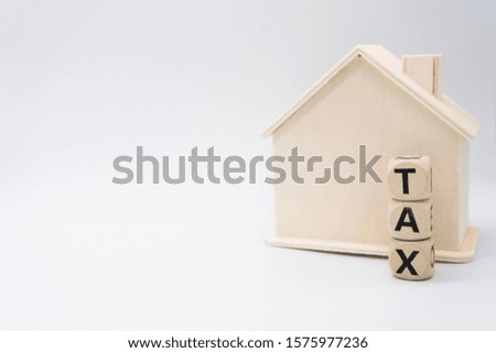 Small model house with tax dice. White background, real estate tax concept