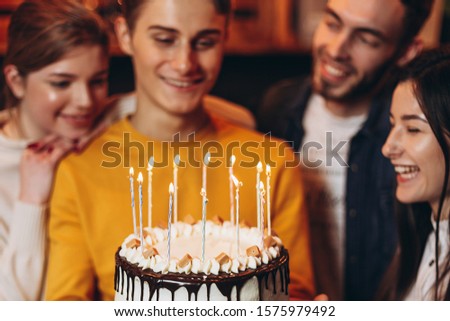 young handsome man holding a cake which he gave his friends for his birthday. Birthday celebration with best friends