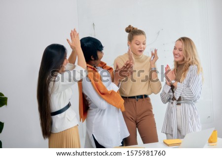 good job of four diverse female working on business project, celebrate their success in office, laptop on table. white office background