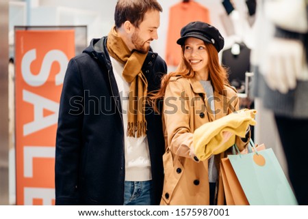 young caucasian couple happily shopping in clothes store together, spend free time in shop. shopaholic concept