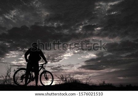 cyclist on the mountain with a bicycle, admiring the fiery sunset.