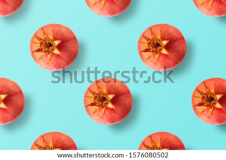 Seamless minimal summer fruits pattern of many whole pomegranate fruits on light blue texture, for blog or recipe book. Horizontal orientation.
