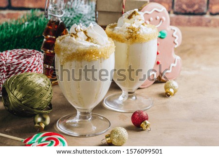 New Year or Christmas Eggnog cocktail - hot winter or autumn drink with milk, eggs and dark rum, sprinkled with spices in glasses on rustic background, festive decoration. Selective focus