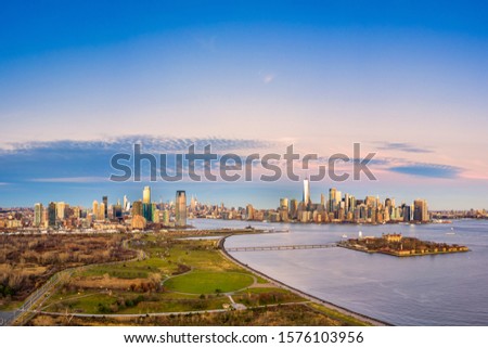 Aerial view of New York City and Jersey City skylines together with Ellis Island, as viewed from above Liberty State Park, in New Jersey, at dusk.
