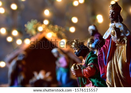 Christmas, silhouette of the The Three Wise Kings. Blurred background of the nativity of Jesus, scene of Bethlehem with the Holy Family and small night lights surrounding them. Frontal vision.