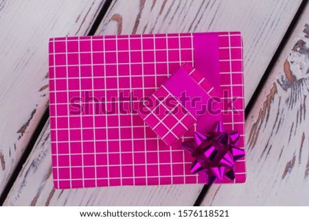 Beautiful gift box on wooden background. Large and small gift boxes wrapped in pink paper with patterns. Christmas holiday gifts.