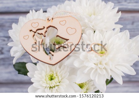 Marriage proposal concept. Gold ring with diamond, white flowers and heart shaped wooden cutout. Happy Valentines Day.