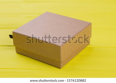 Cardboard box on yellow wood background. Close up.