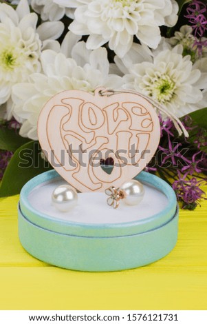 Romantic background with gift and flowers. Jewelry box with pearl earrings, wooden heart and bouquet of flowers close up. Valentines Day background.