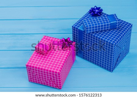 Two checkered gift boxes. Pink and blue. Blue wooden surface background.