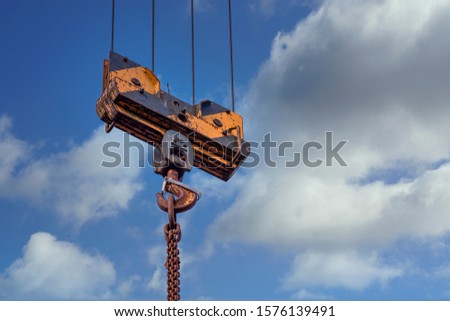 Pulley of a tower crane with fastening hook and chain.